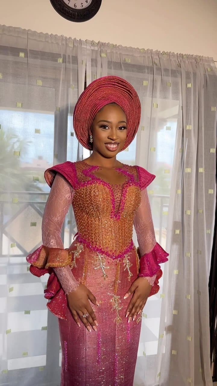 Bride in a coral and gold traditional gown with matching gele